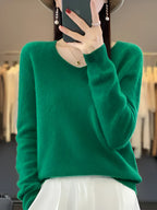 A woman wearing a luxurious emerald green cashmere sweater, showcasing its soft and elegant design.