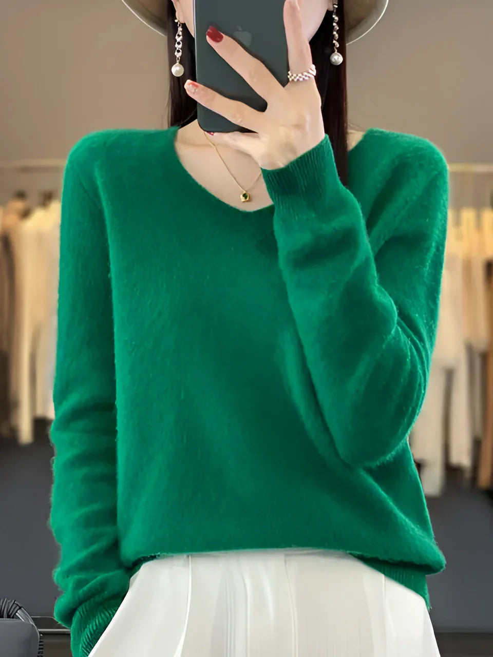 A woman wearing a luxurious emerald green cashmere sweater, showcasing its soft and elegant design.